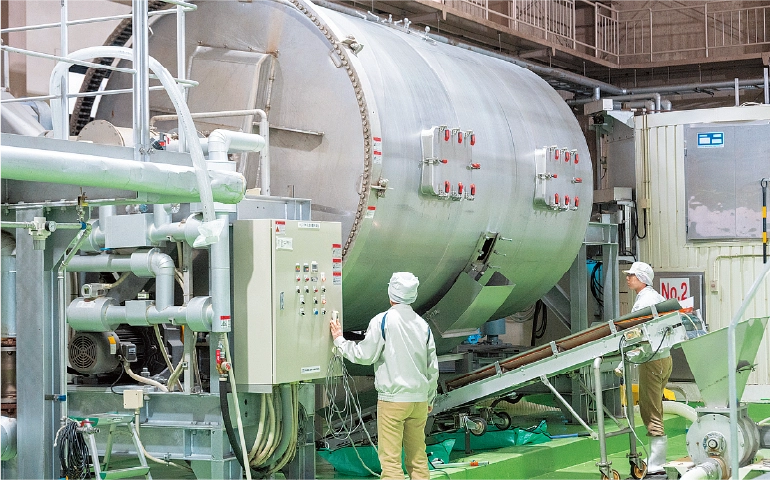 回転ドラム式蒸し機を操作する様子